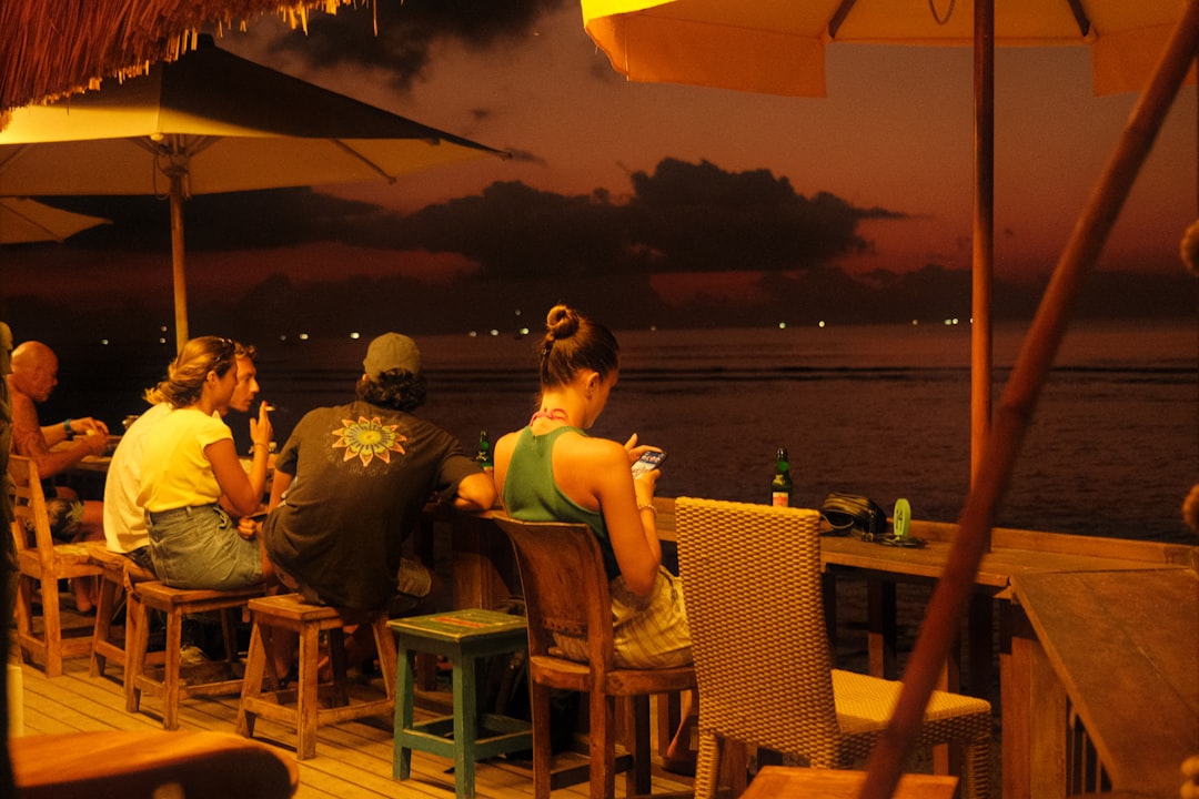 People at a beach bar by the ocean at dusk